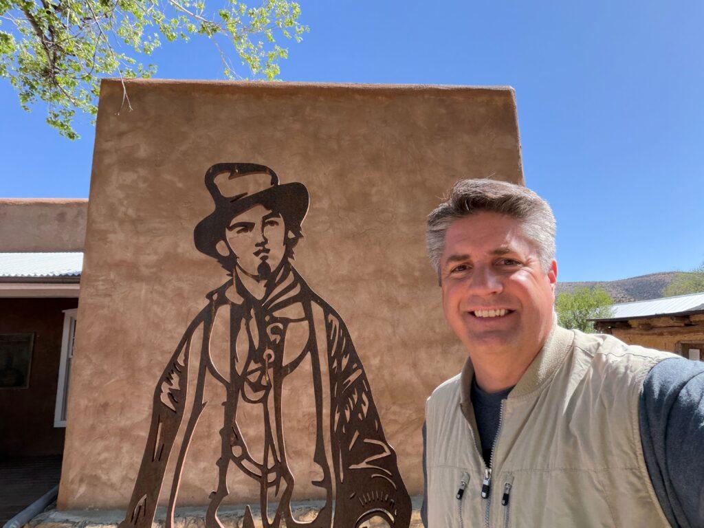 man standing next to metal silhousette of Billy the Kid