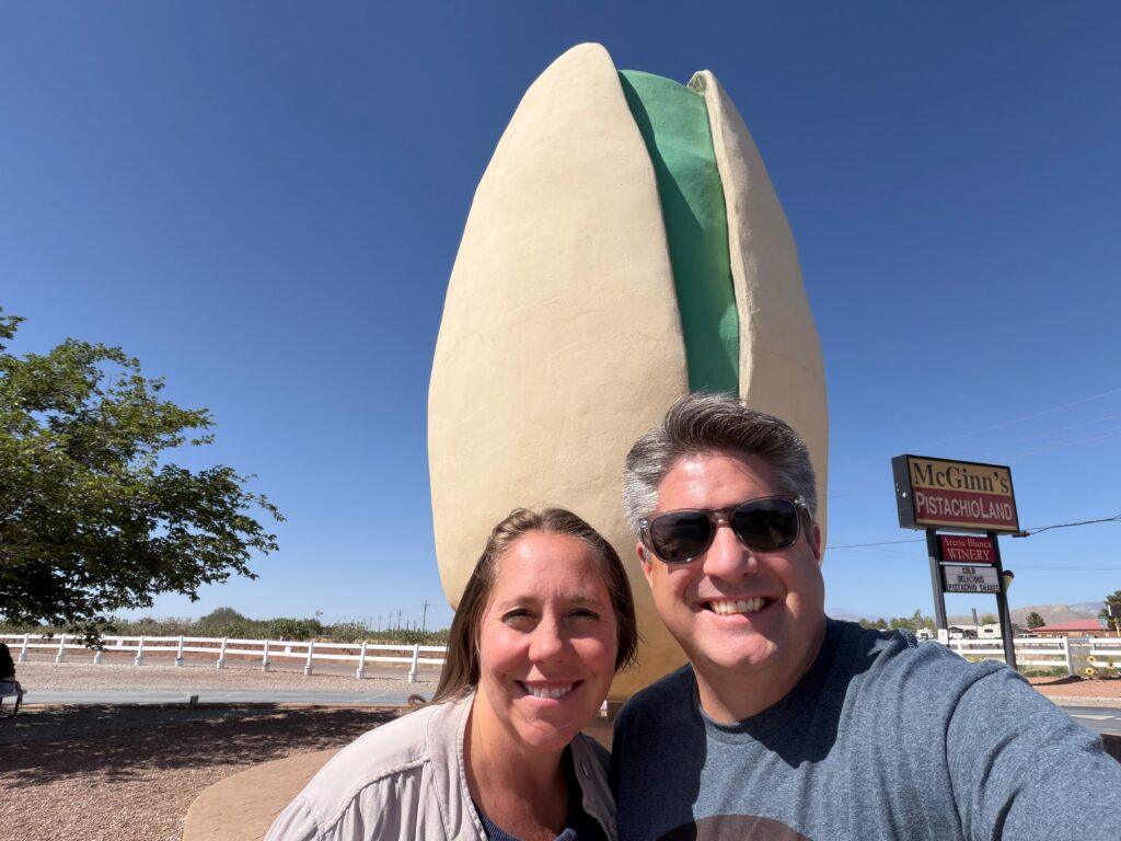man and woman in front of large pistachio statue
