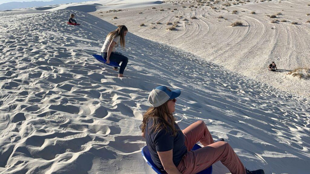 ladies riding sleds down sand hill