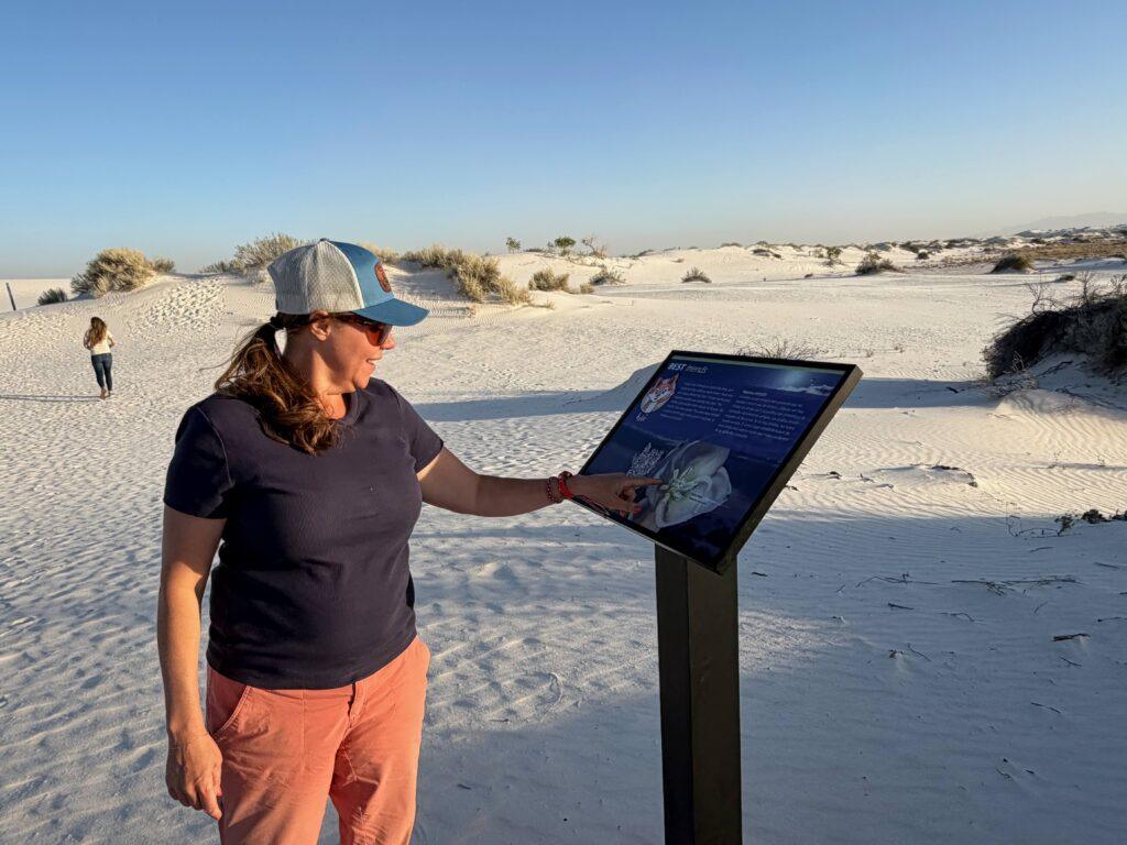 woman reading informational sign in sand dunes