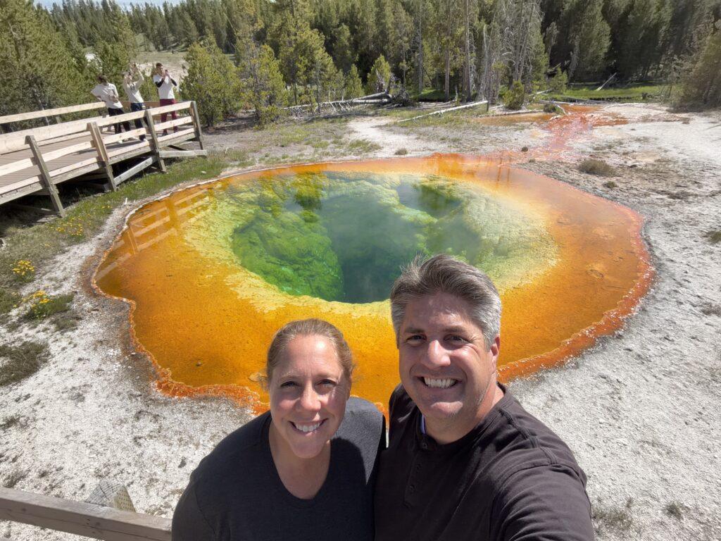 man and woman in front of colorful pool in Yellowstone