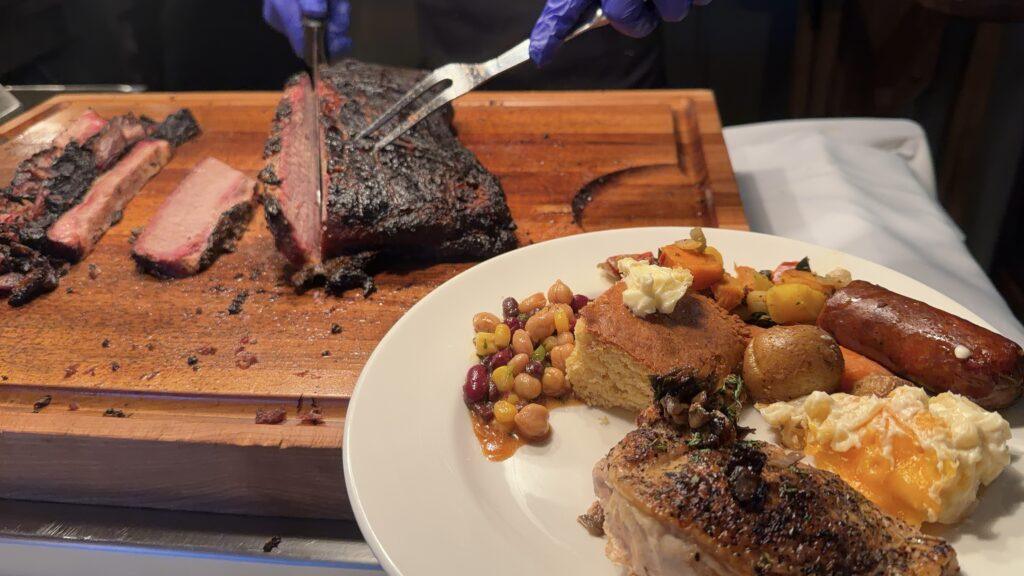 brisket being carved with plate of food next to it