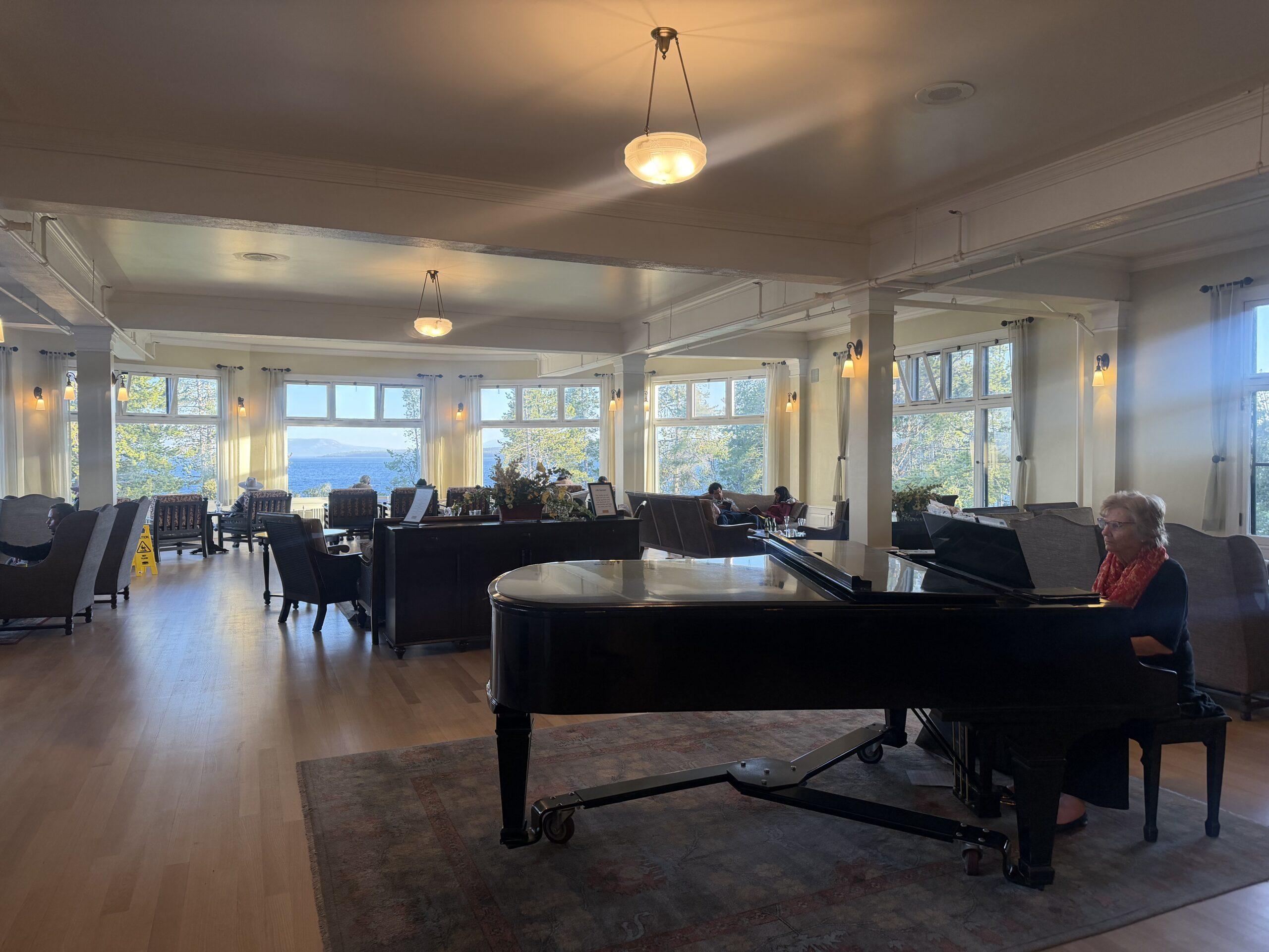 woman playing grand piano in lobby of hotel