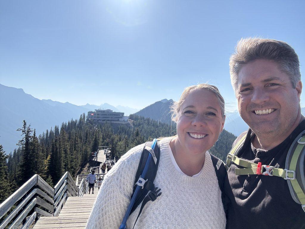 man and woman on boardwalk on mountaintop