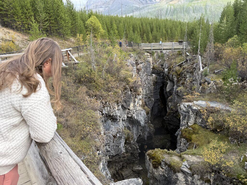 woman standing on bridge looking down in to narrow canyon