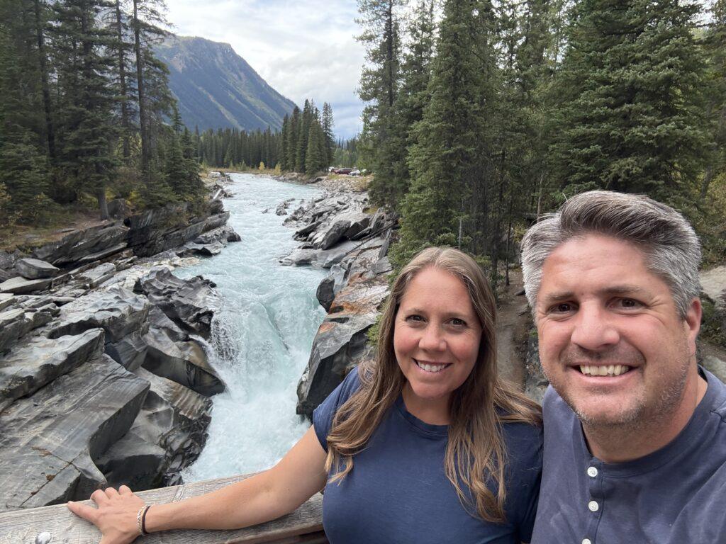 man and woman in front of waterfall