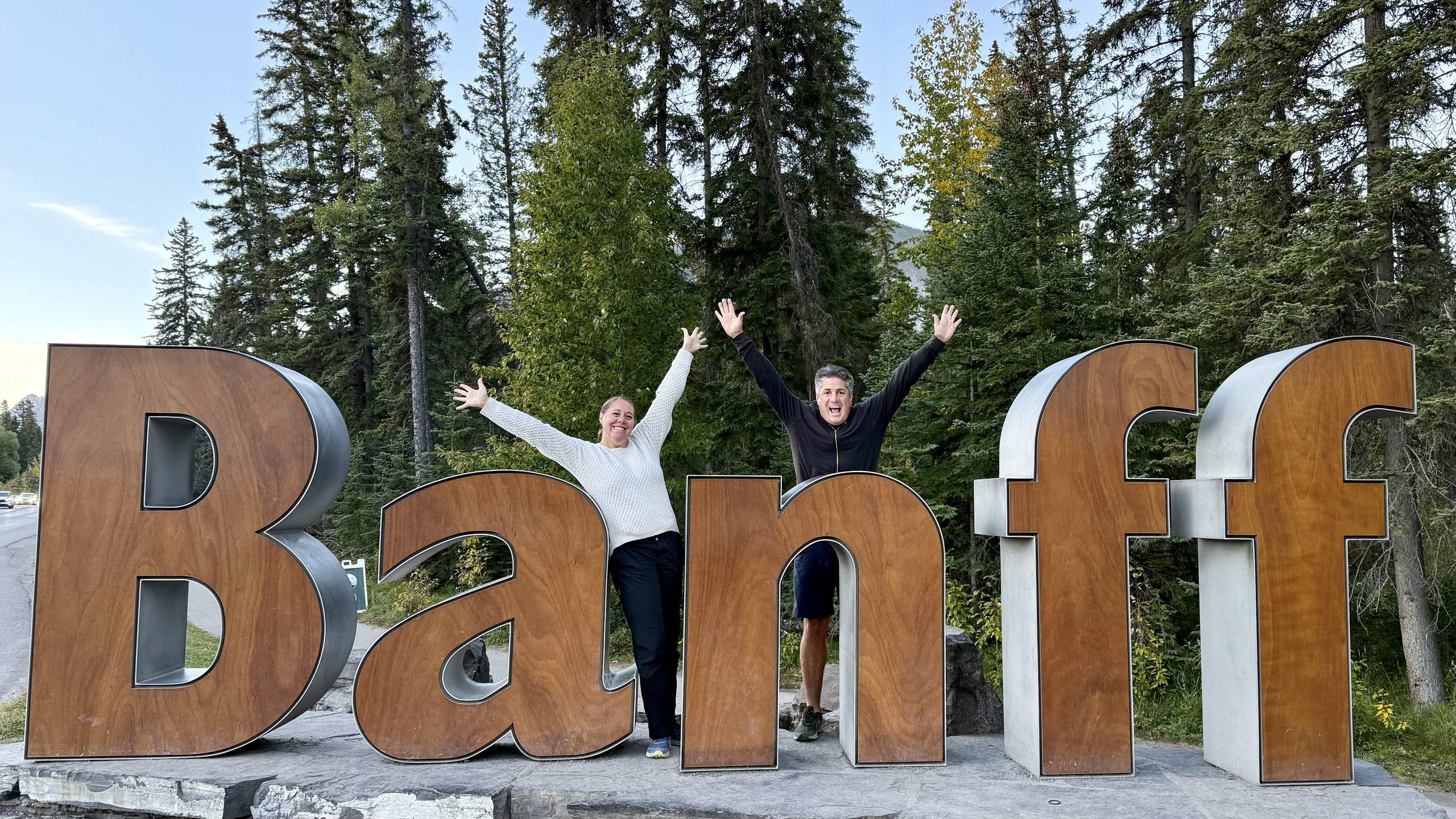 man and woman standing in between letters of Banff sign