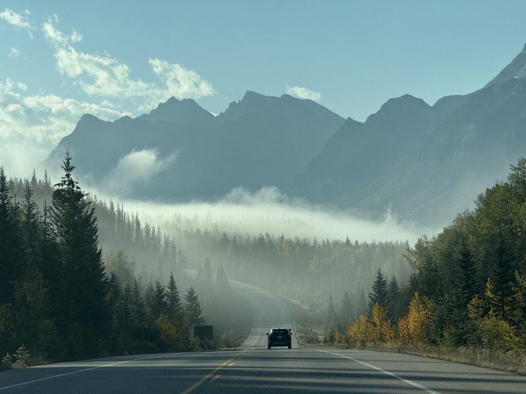car driving down road in mountain canyon in mist