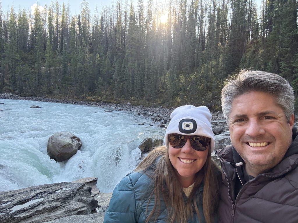 man and woman in front of waterfall