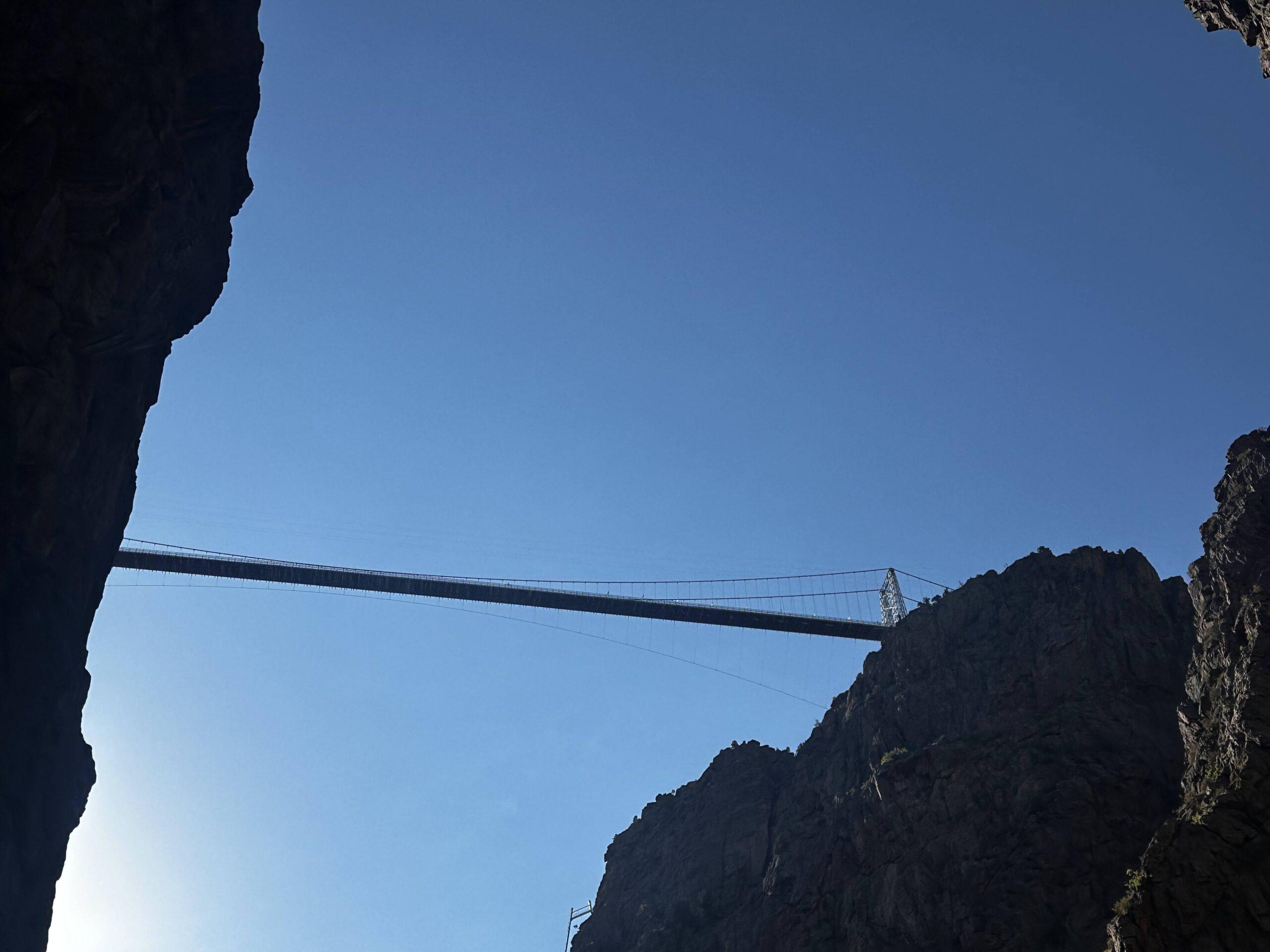 Royal Gorge suspension bridge spanning the sky between steep canyon walls, viewed from below