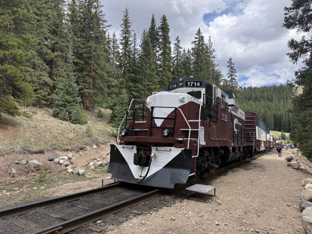 Leadville Railroad locomotive 1714 with maroon and white paint beside pine trees.