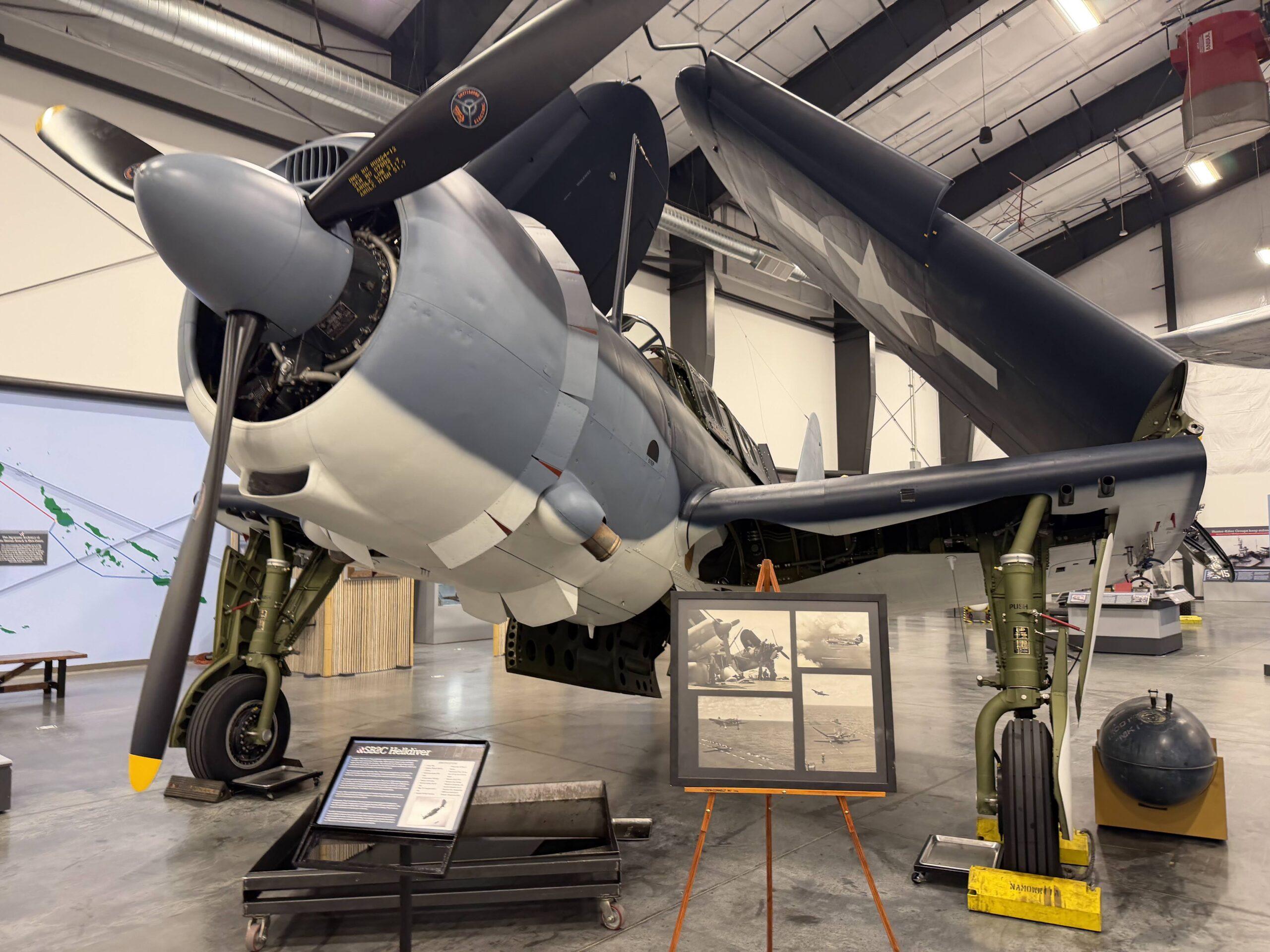 Historic propeller aircraft with folded wings inside the National Museum of World War II Aviation