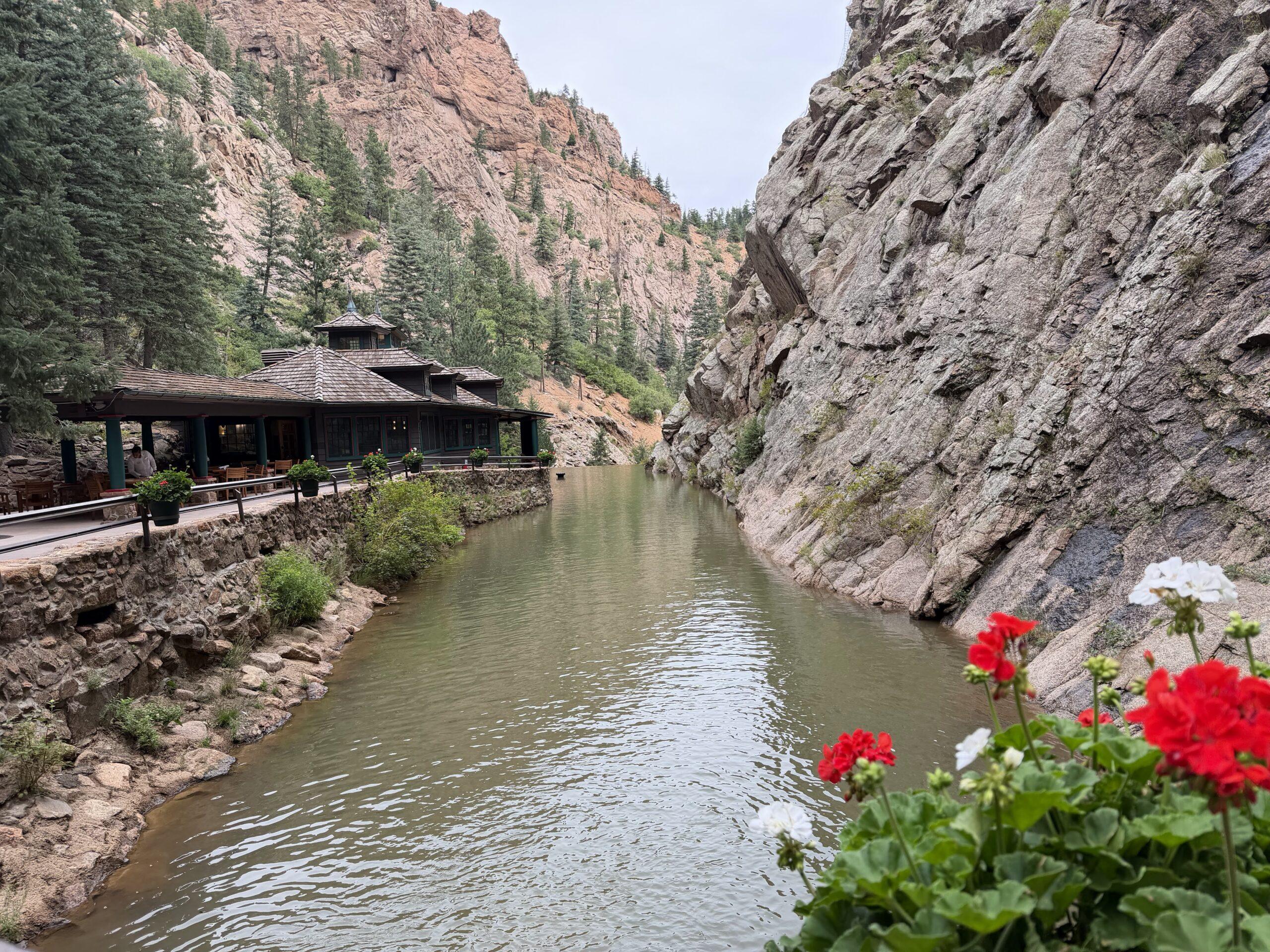 Creek, red flowers, and tall canyon walls along the approach to Seven Falls