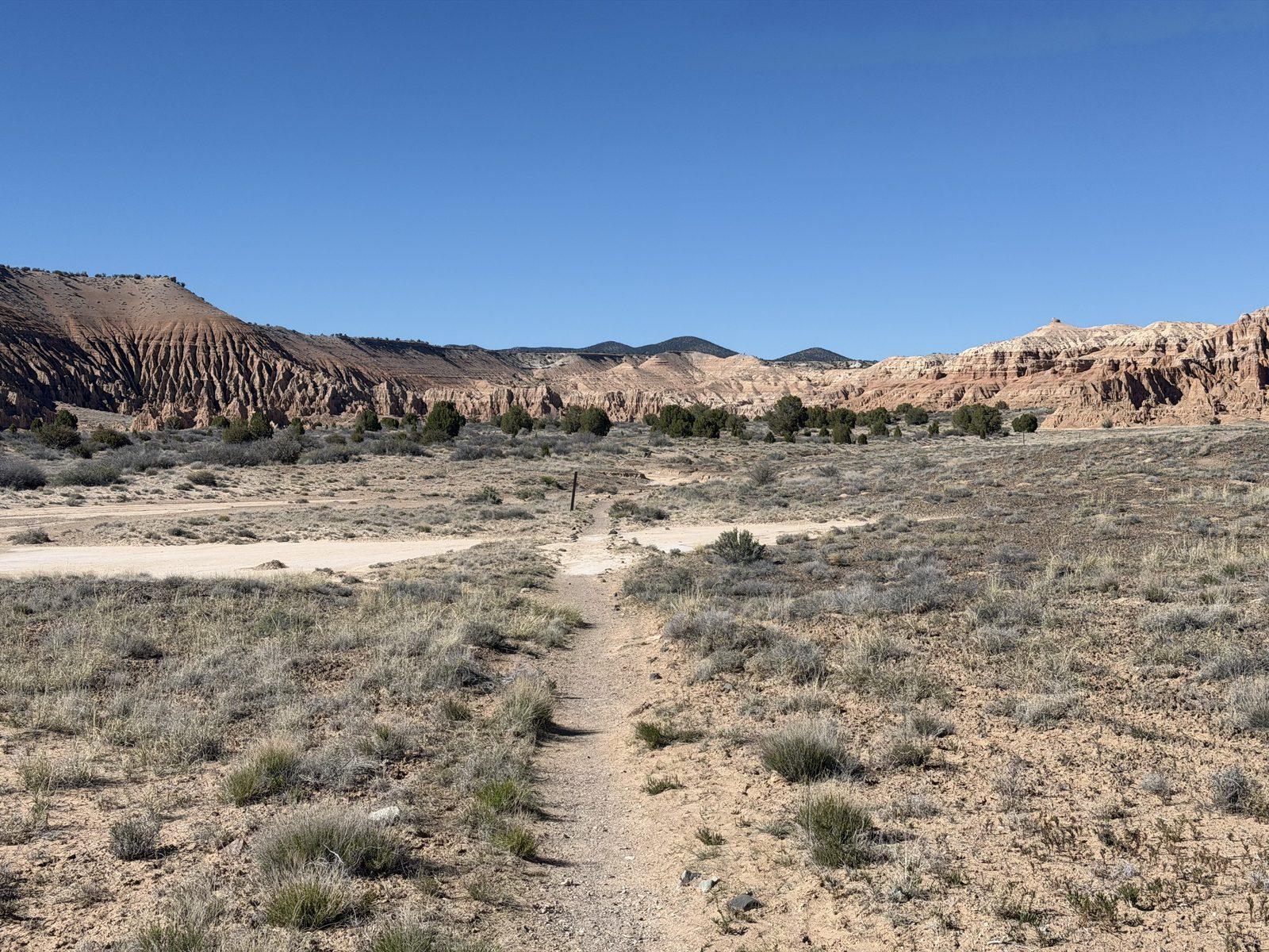 Sandy Juniper Draw Loop trail winds through desert scrub beneath Cathedral Gorge formations.