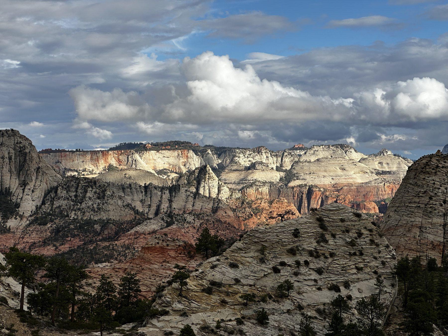 Layered sandstone cliffs and forested slopes beneath clouds at the Northgate Peaks overlook.